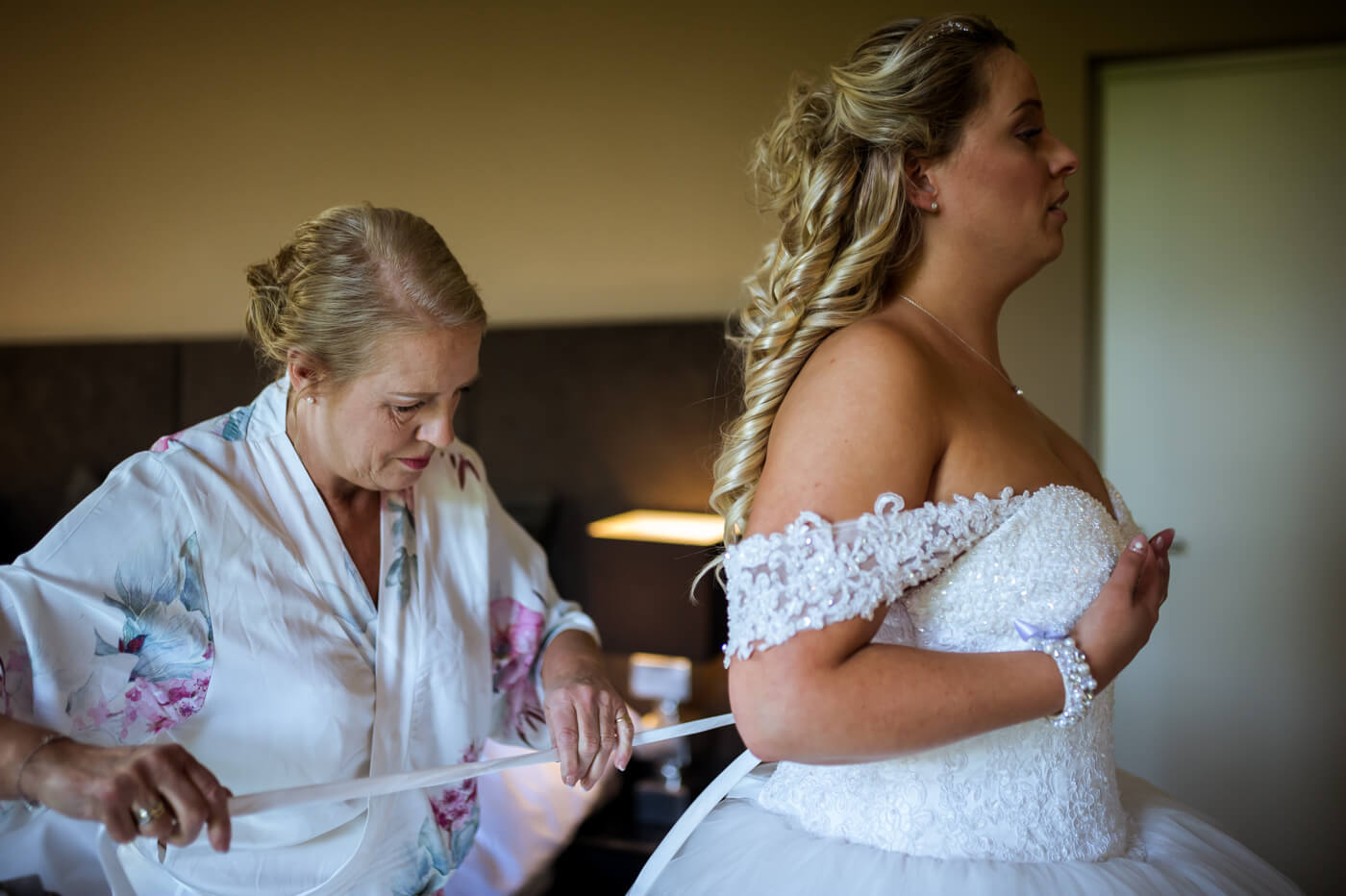 moeder bruid maakt trouwjurk vast
